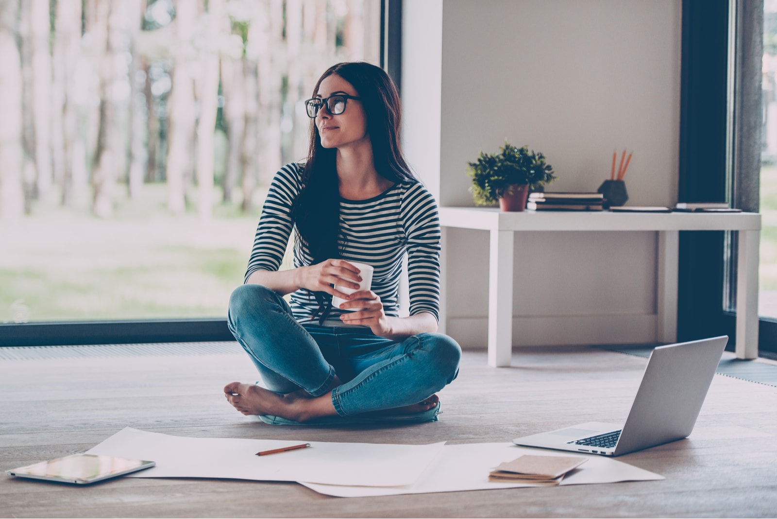 brunette with glasses on the floor sitting and arranging something on her laptop