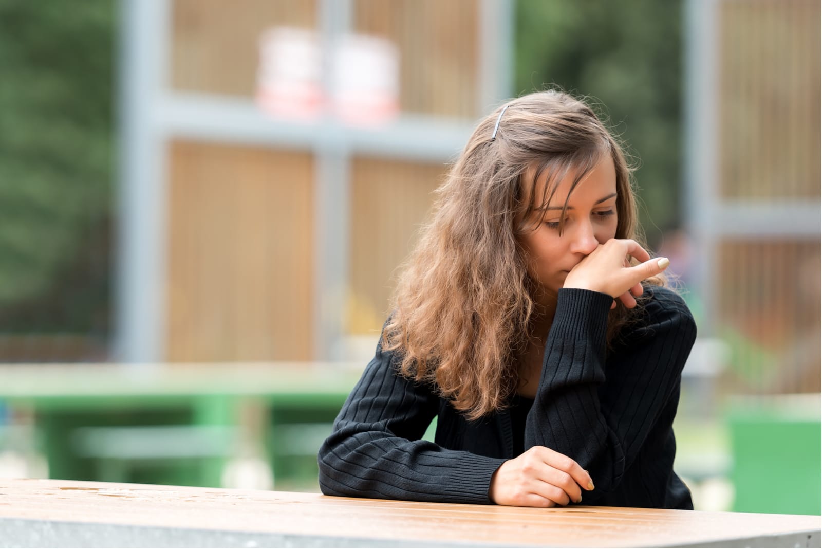 a sad brunette is sitting outside at the table