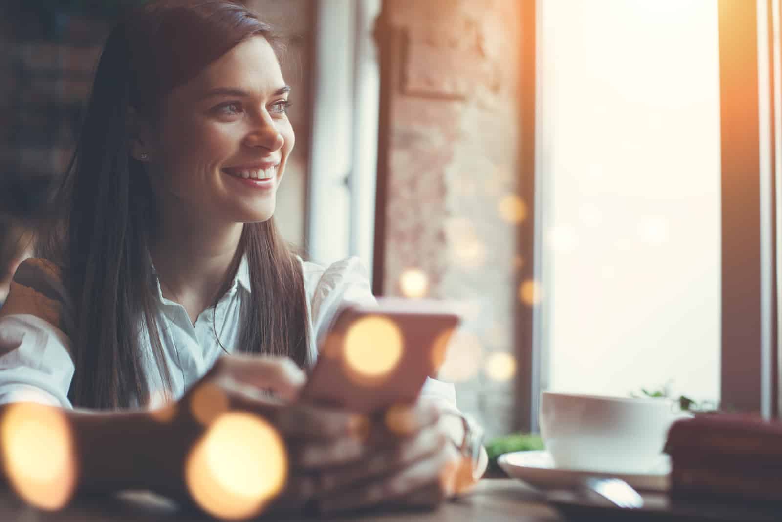 smiling woman in cafe using mobile phone