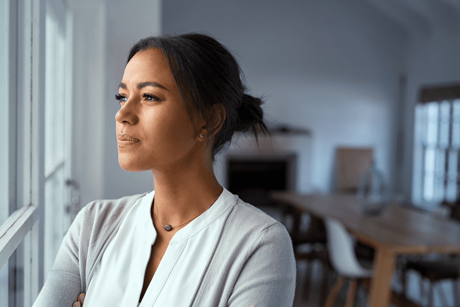 a pensive woman stands by the window