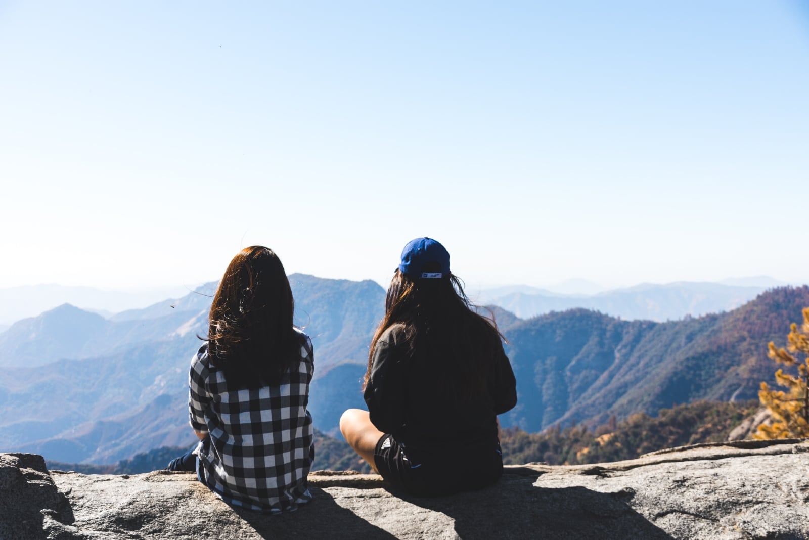 two women talking while sitting on rock