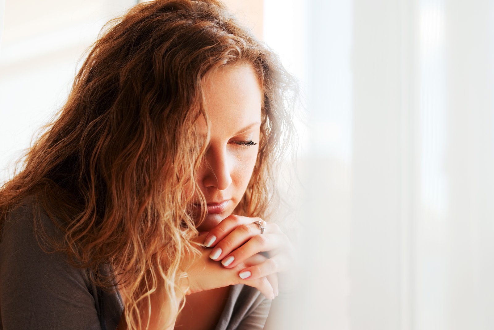 a woman with long brown hair with a downcast look