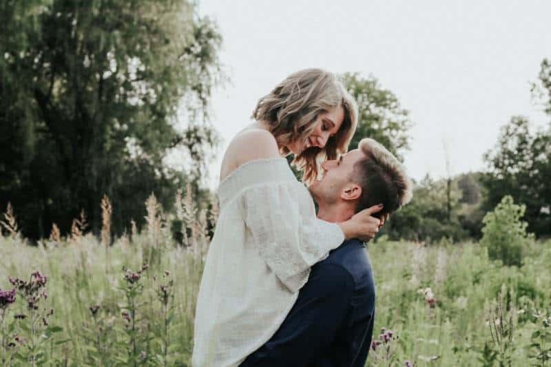 Couple kissing in a field, surrounded by nature