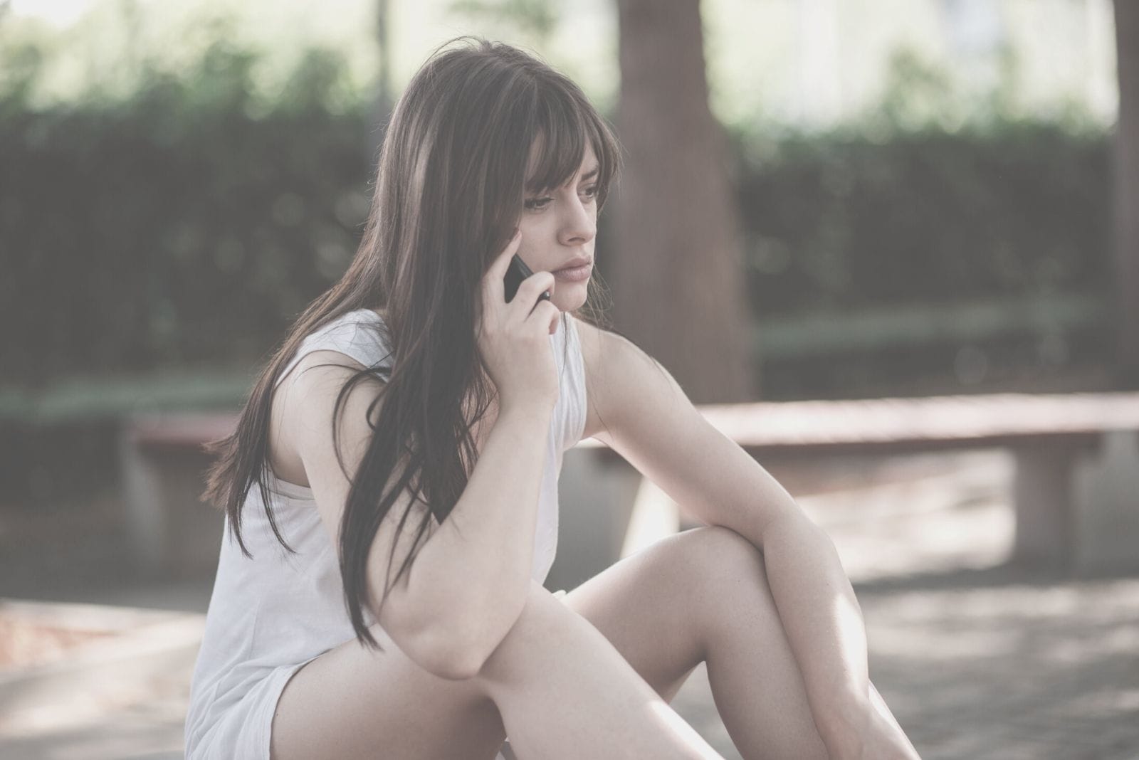 sad woman listening to the phone on the other line while sitting outdoors