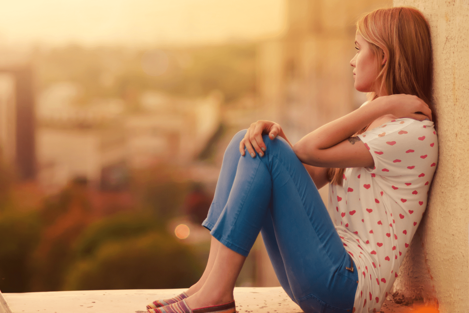 a woman with long brown hair leaning against the wall is thinking