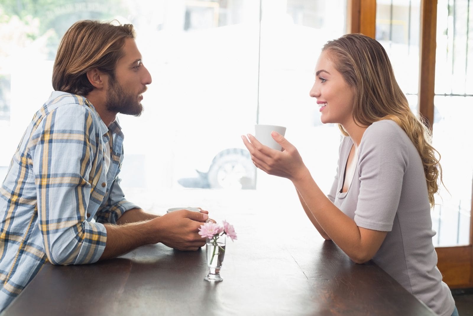 couple sitting face to face in a cafe, talking and smiling