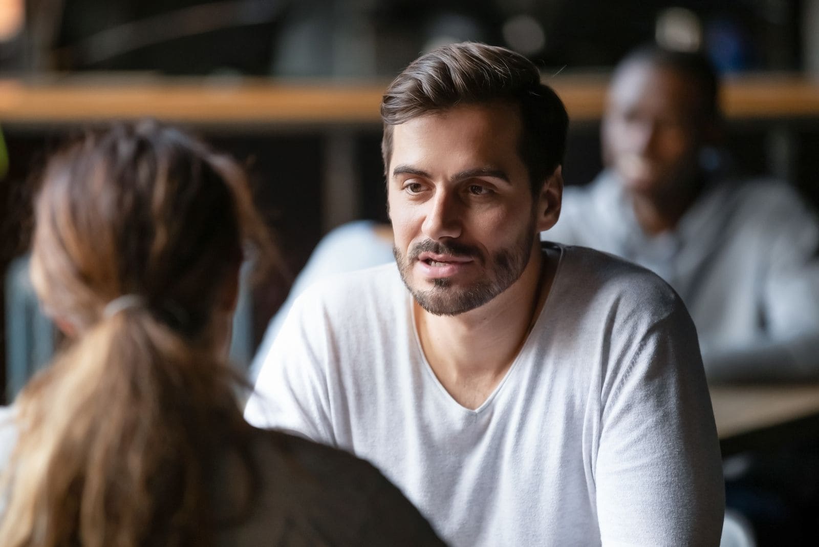 young serious man talking with a woman in a cafe