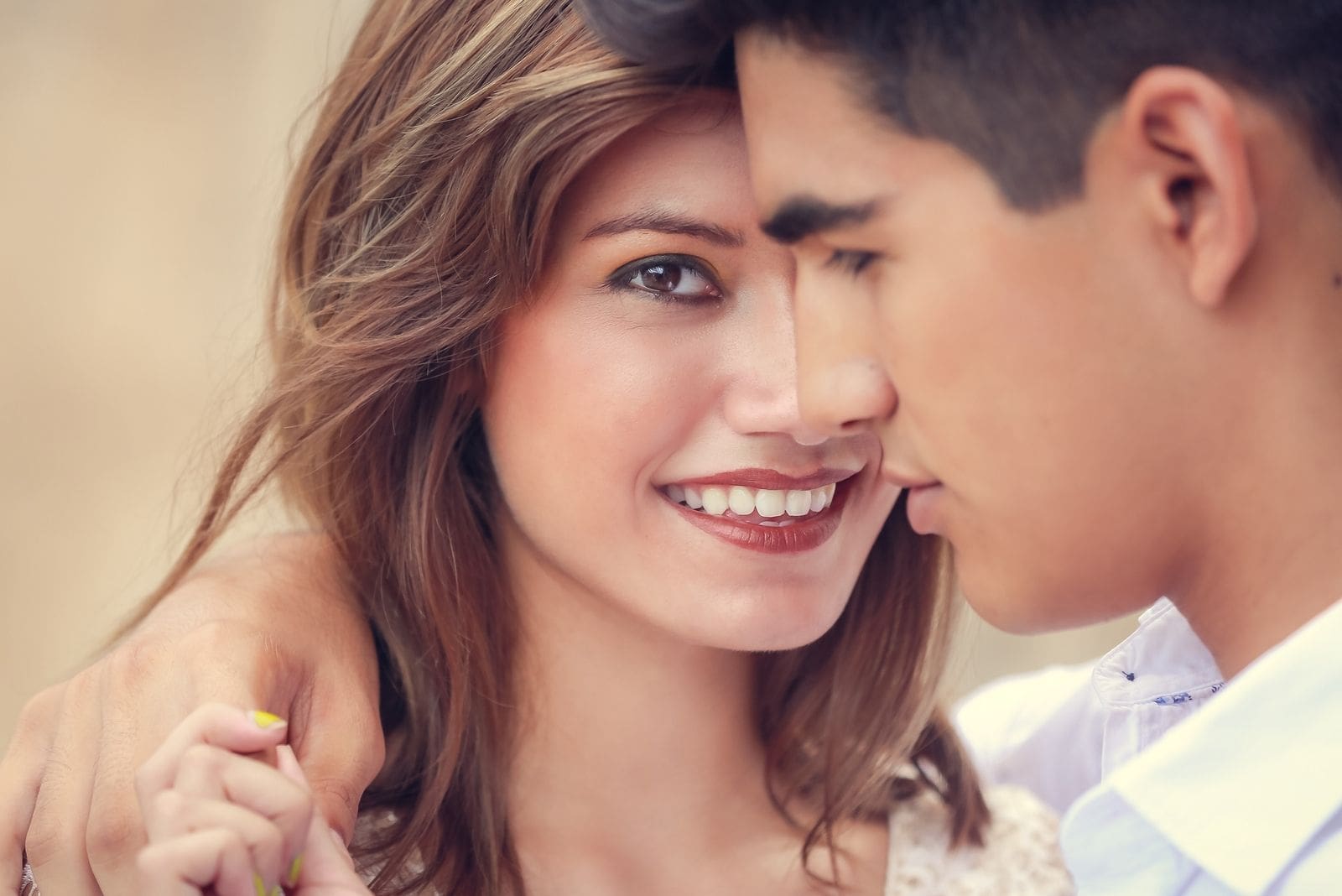 beautiful woman's face close to a man with hand hand around her shoulder