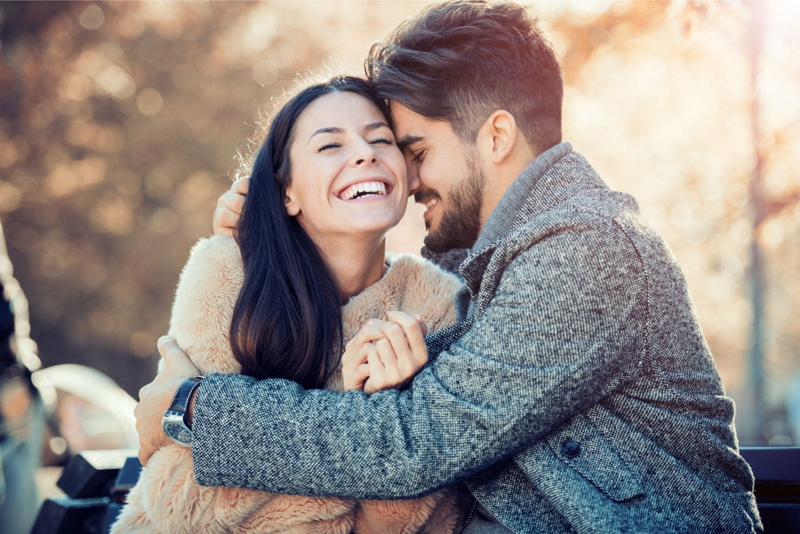 happy romantic couple hugging and laughing sitting outdoors