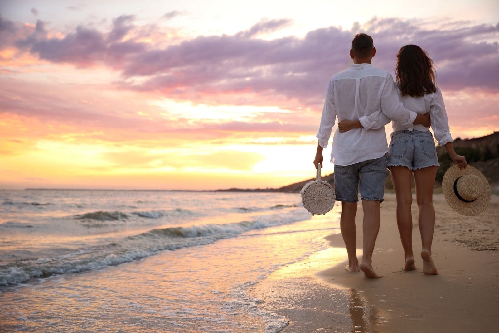 lovely couple walking on the beach side by side during sunset