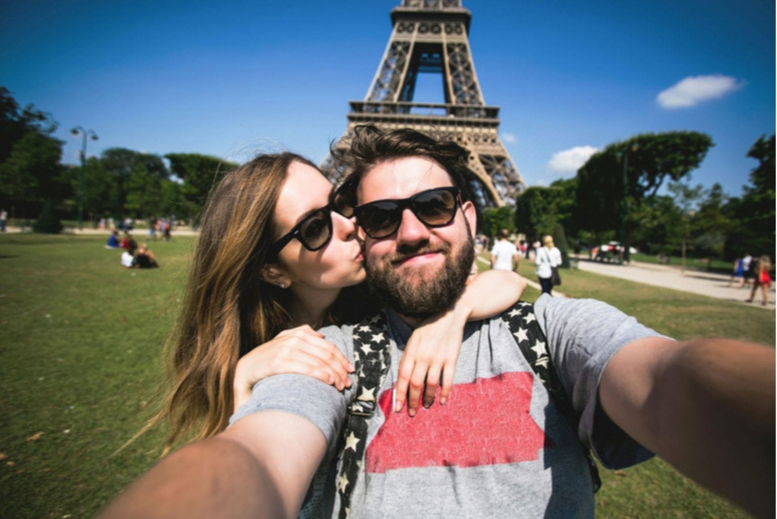 couple at the eiffel tower France posing with the woman kissing and hugging the man