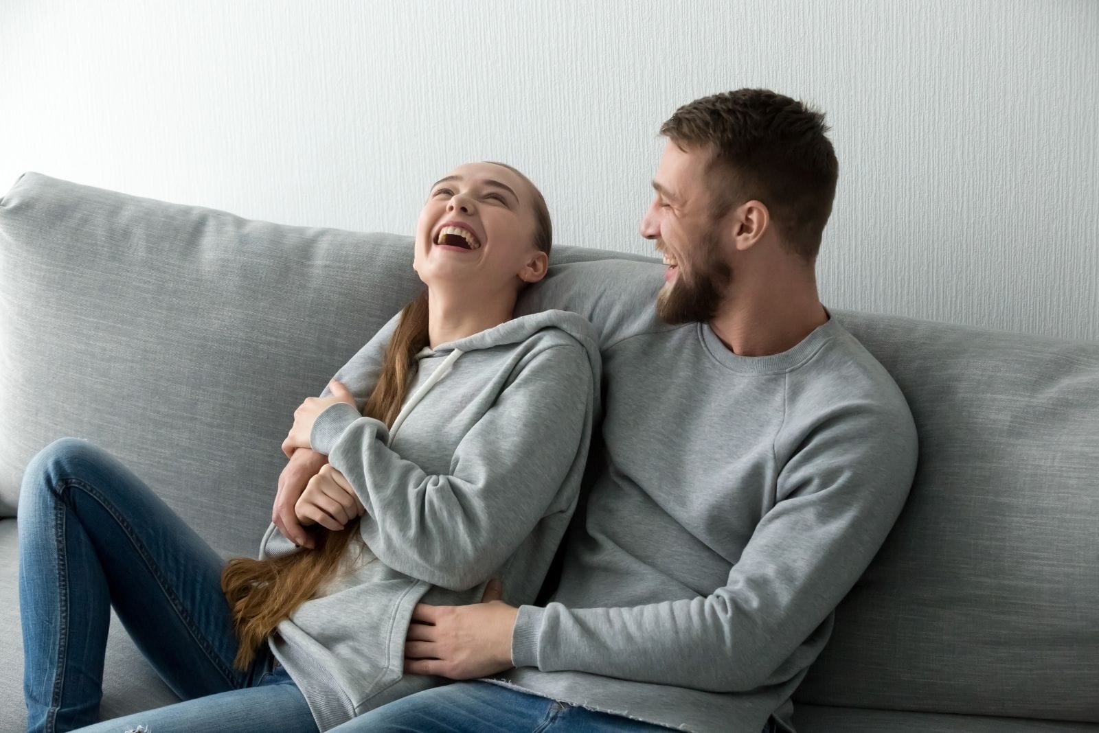 cheerful couple laughing and chilling in the gray couch