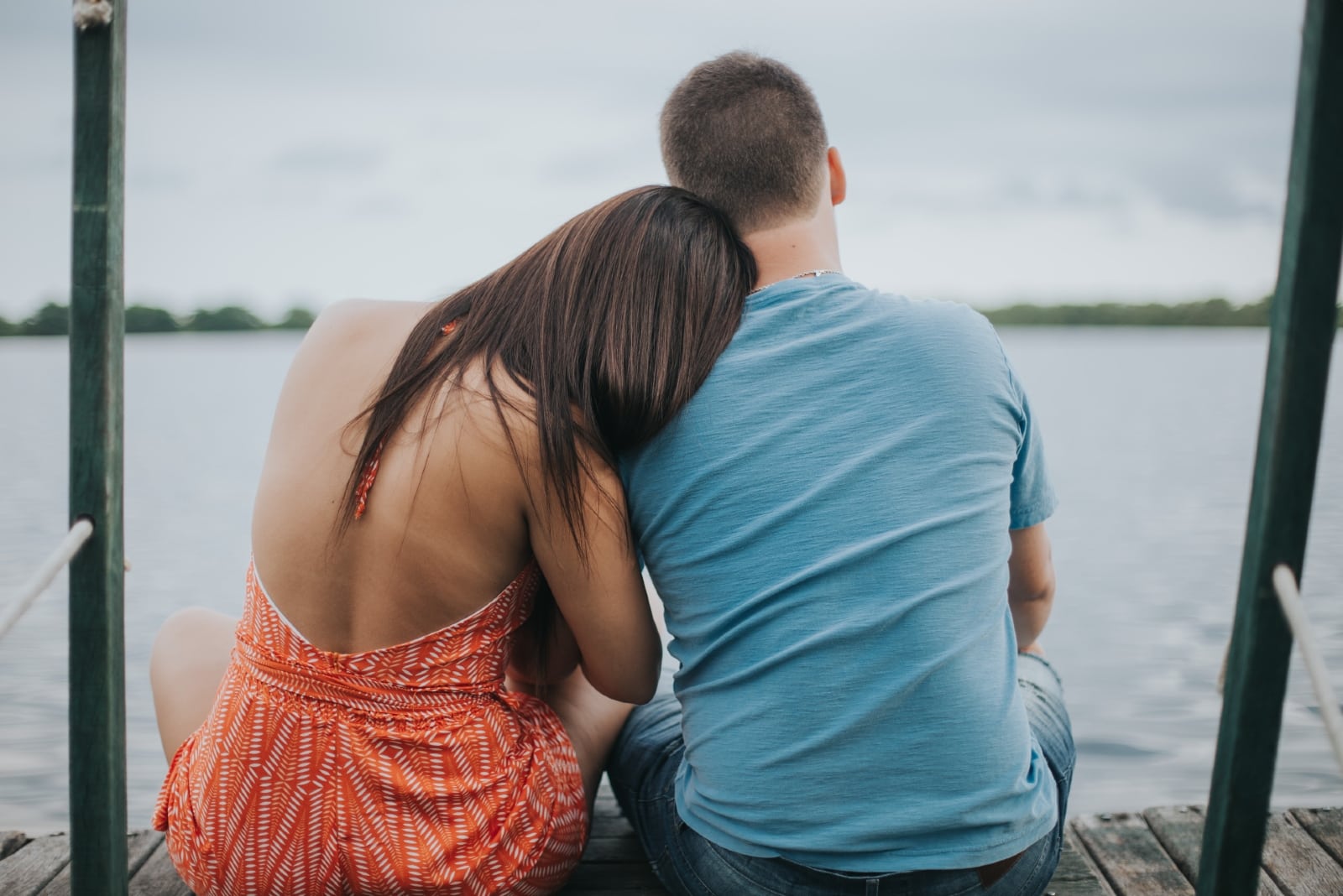 man and woman sitting on dock looking at water
