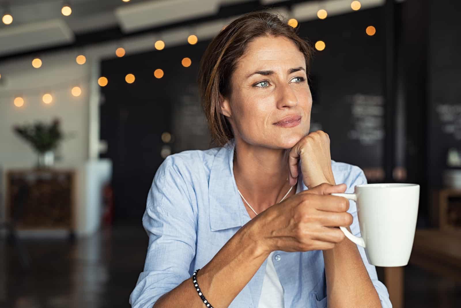 an imaginary woman sitting at a table drinking coffee