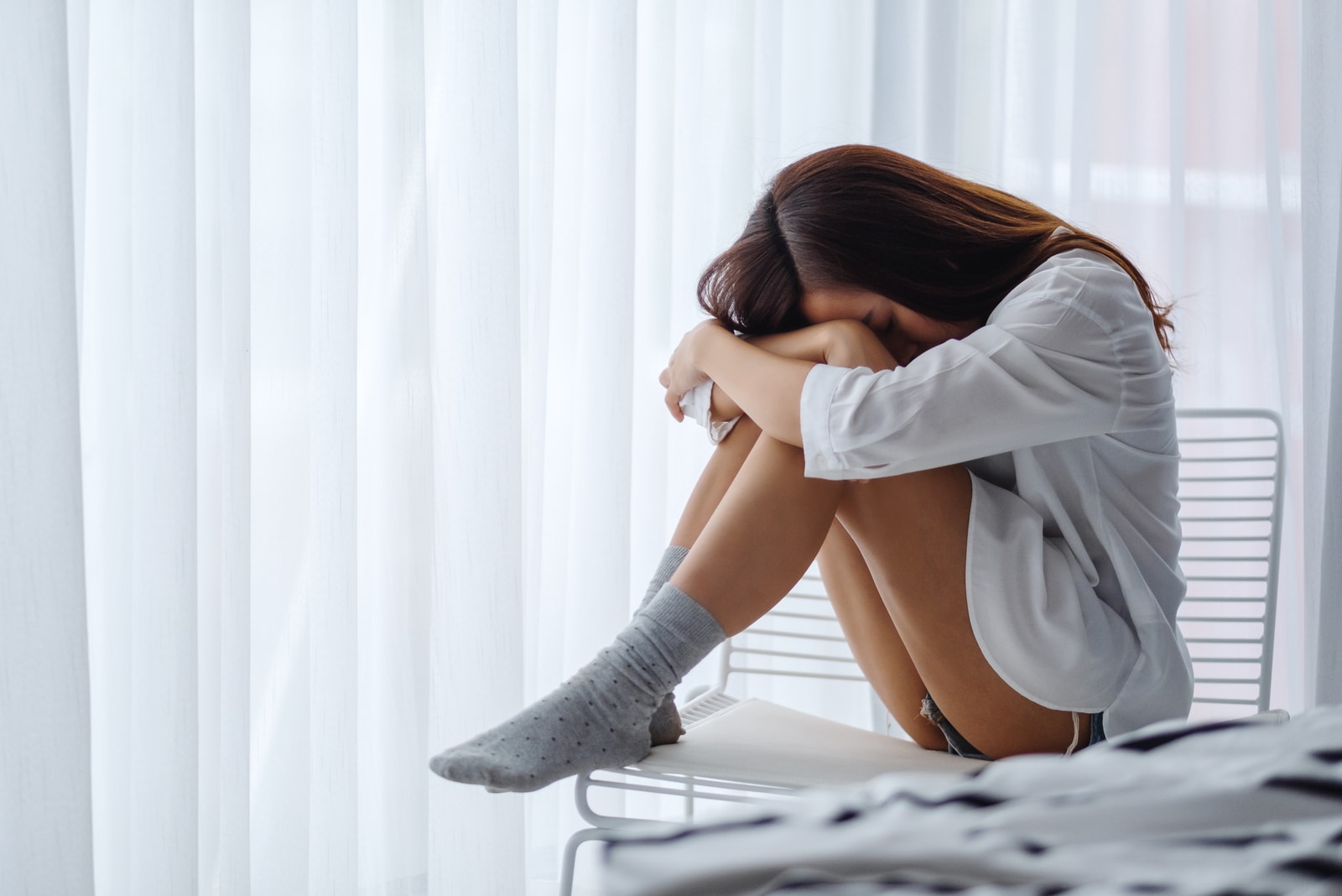 the woman sits in a chair with her head down