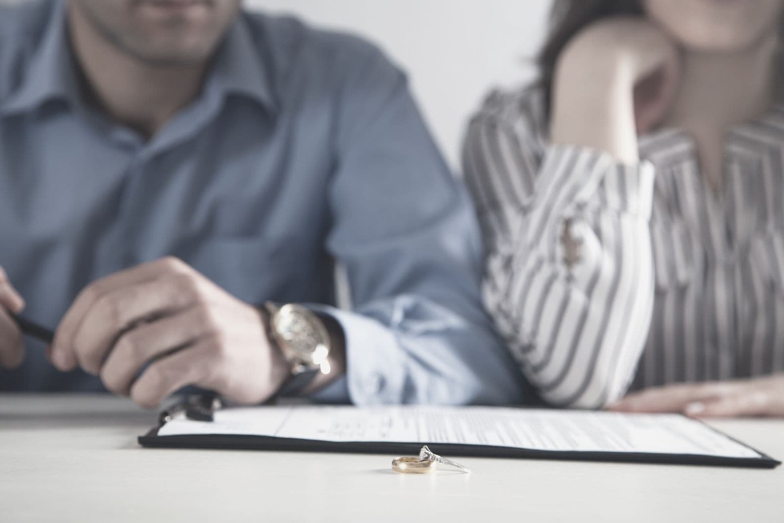 couple with divorce contract and a ring on the table in cropped image