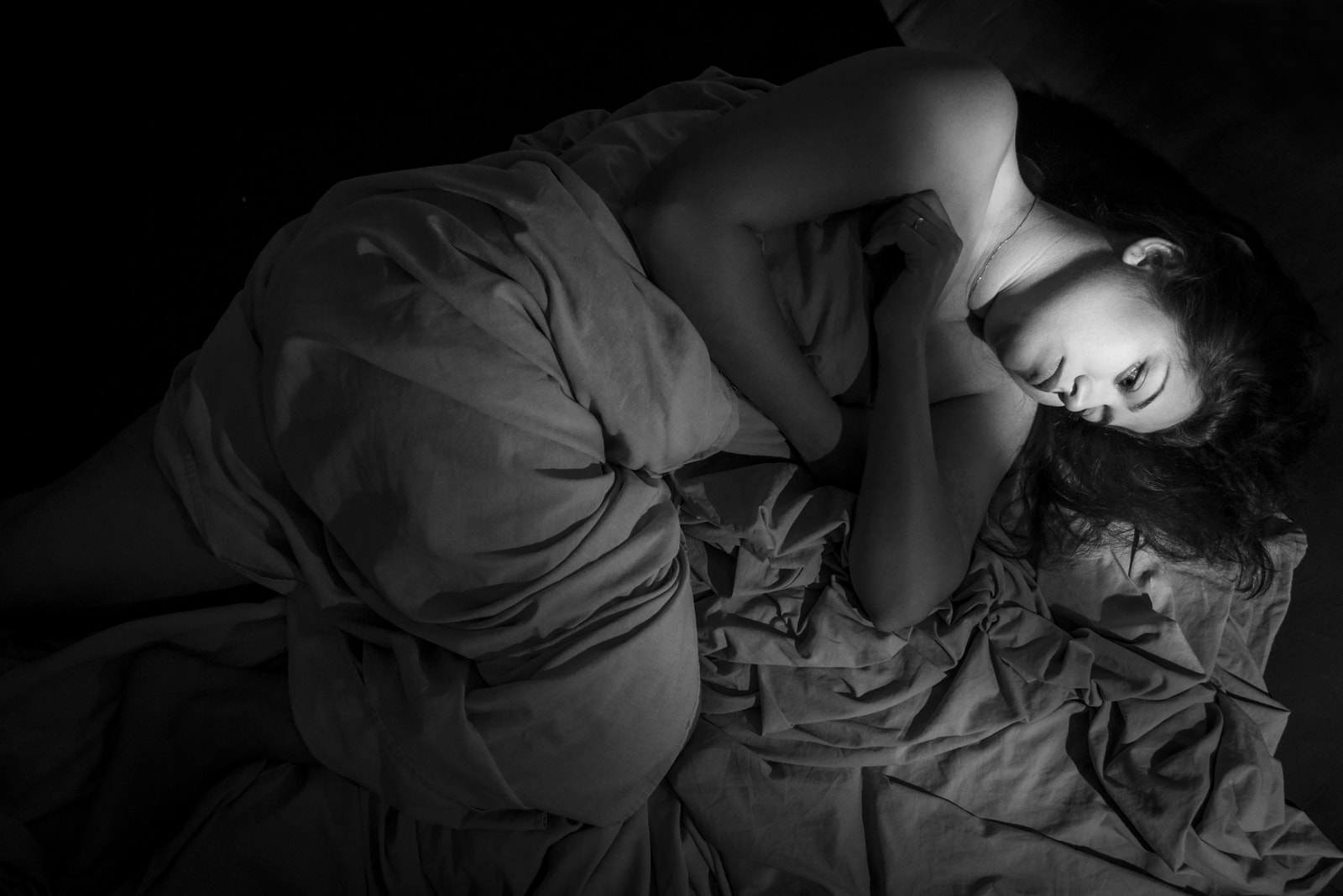 a depressed sad brunette is lying in bed