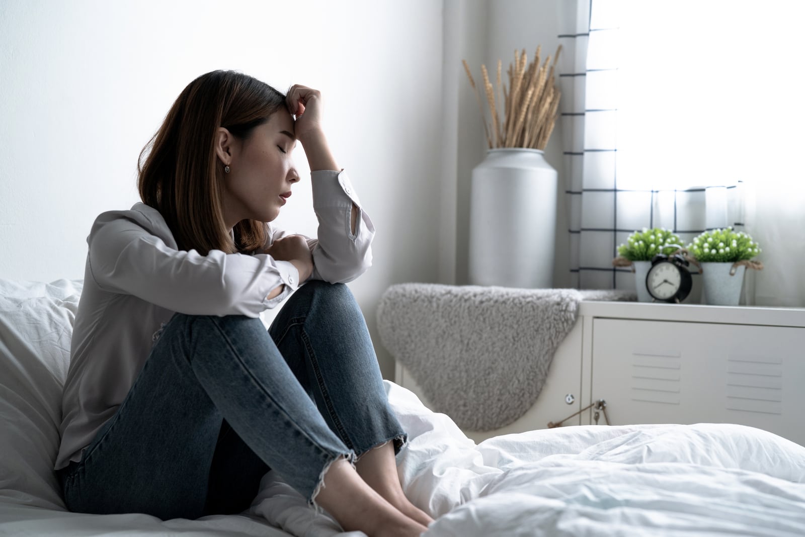 a sad Asian girl sits on the bed and suffers