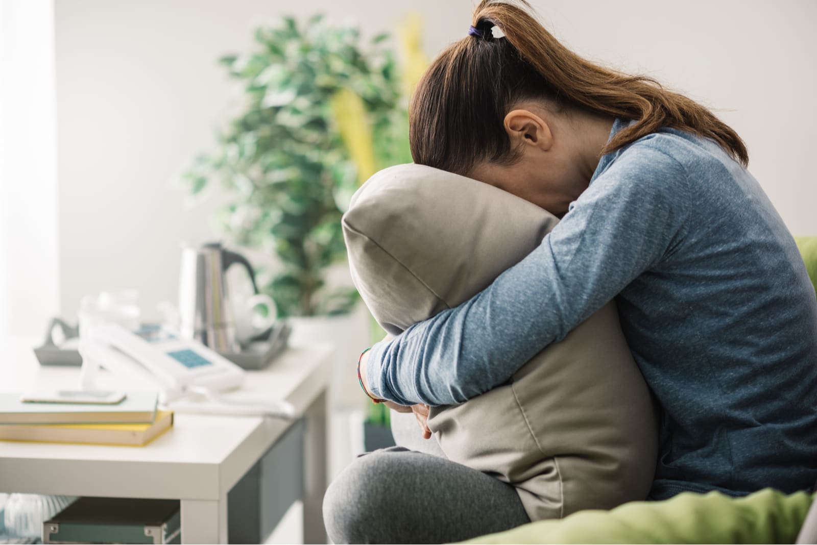 sad young woman hugging pillow on the couch