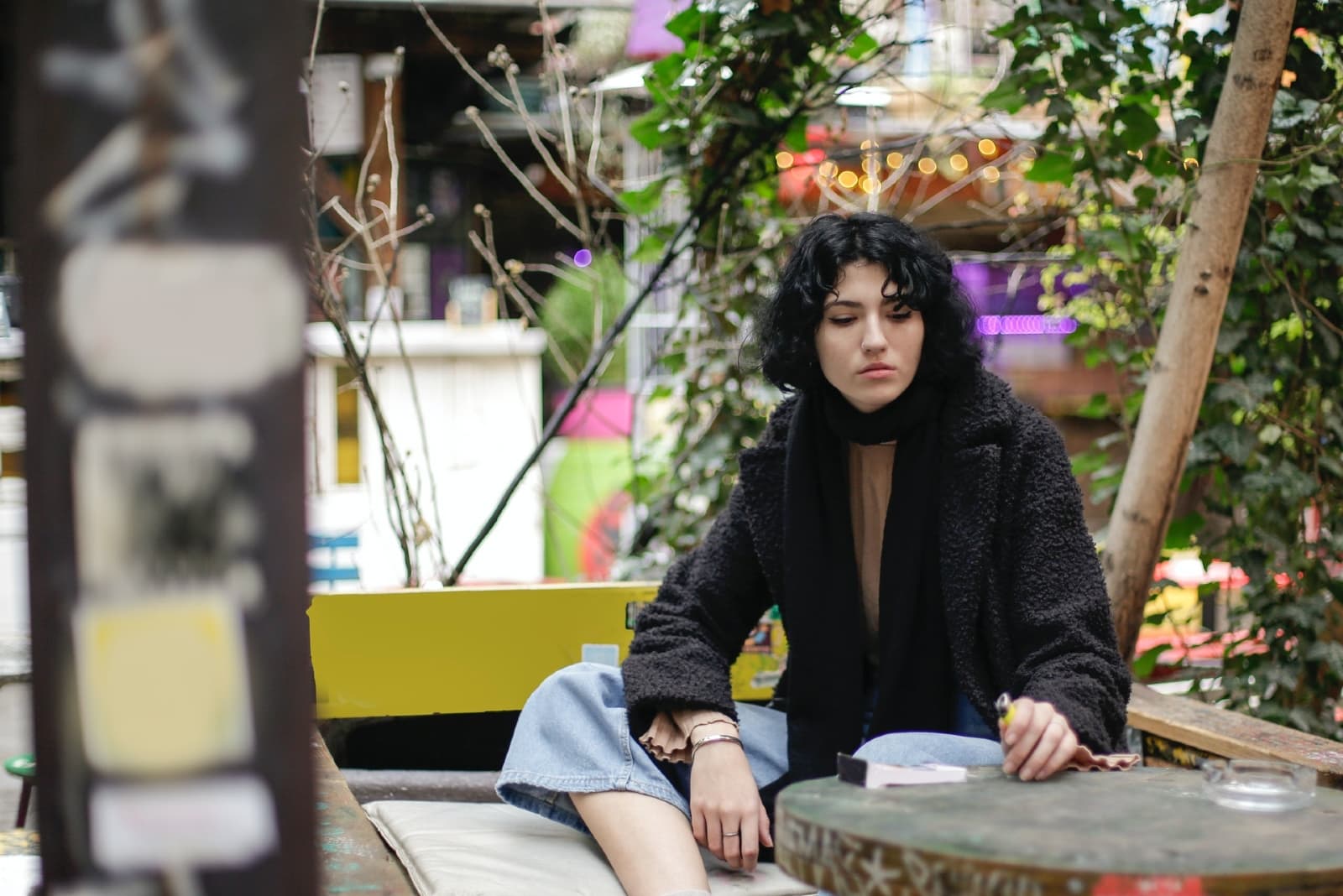woman holding lighter while sitting on bench outdoor