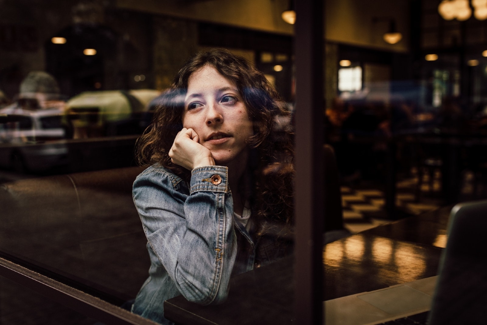 woman leaning on table while sitting in cafe