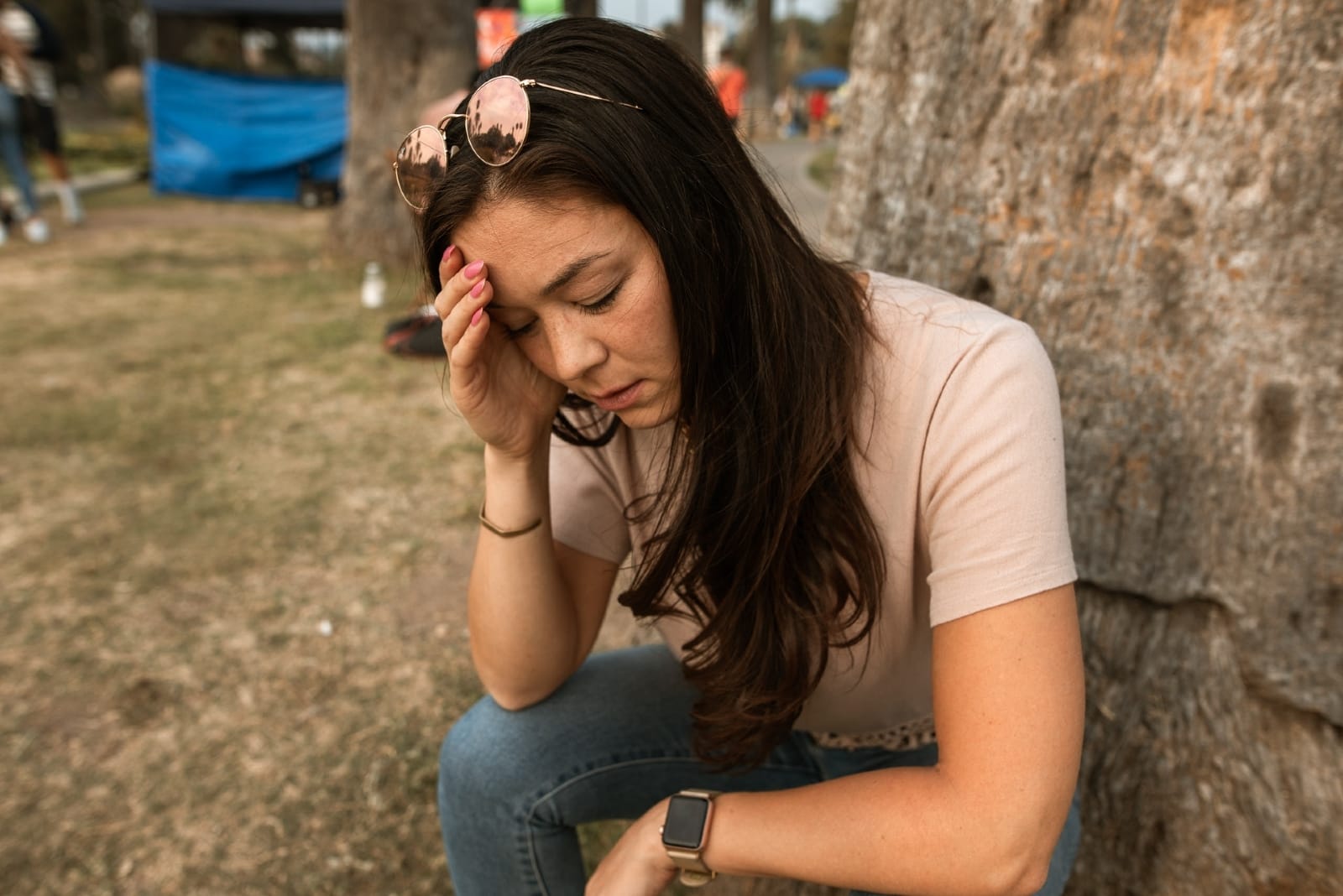 concerned woman in white t-shirt sitting near tree