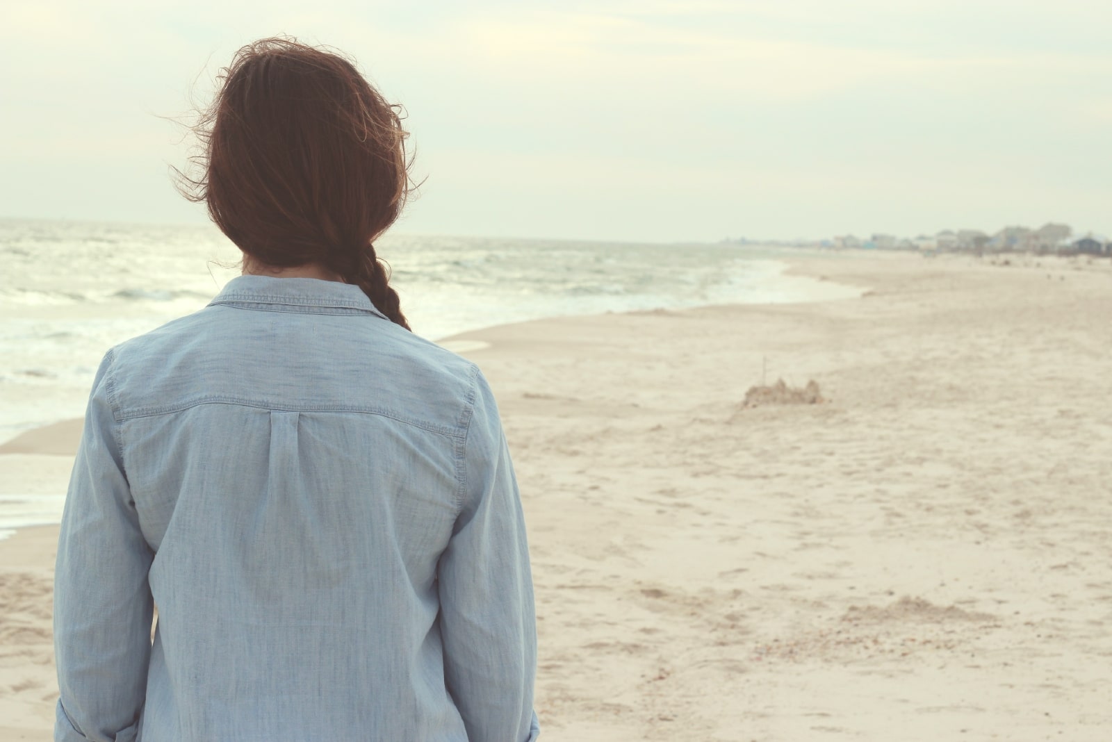 woman in denim shirt looking at the ocean